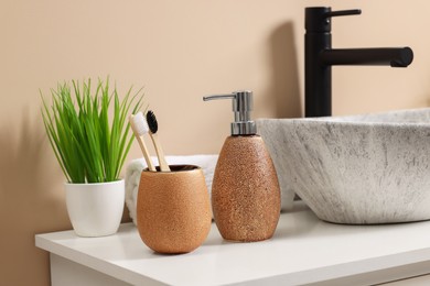 Different bath accessories and personal care products near sink on bathroom vanity