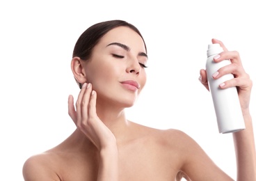 Young woman applying thermal water on face against white background. Cosmetic product