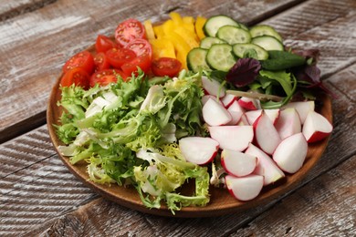 Photo of Vegetarian diet. Plate with tasty vegetables on wooden table, closeup