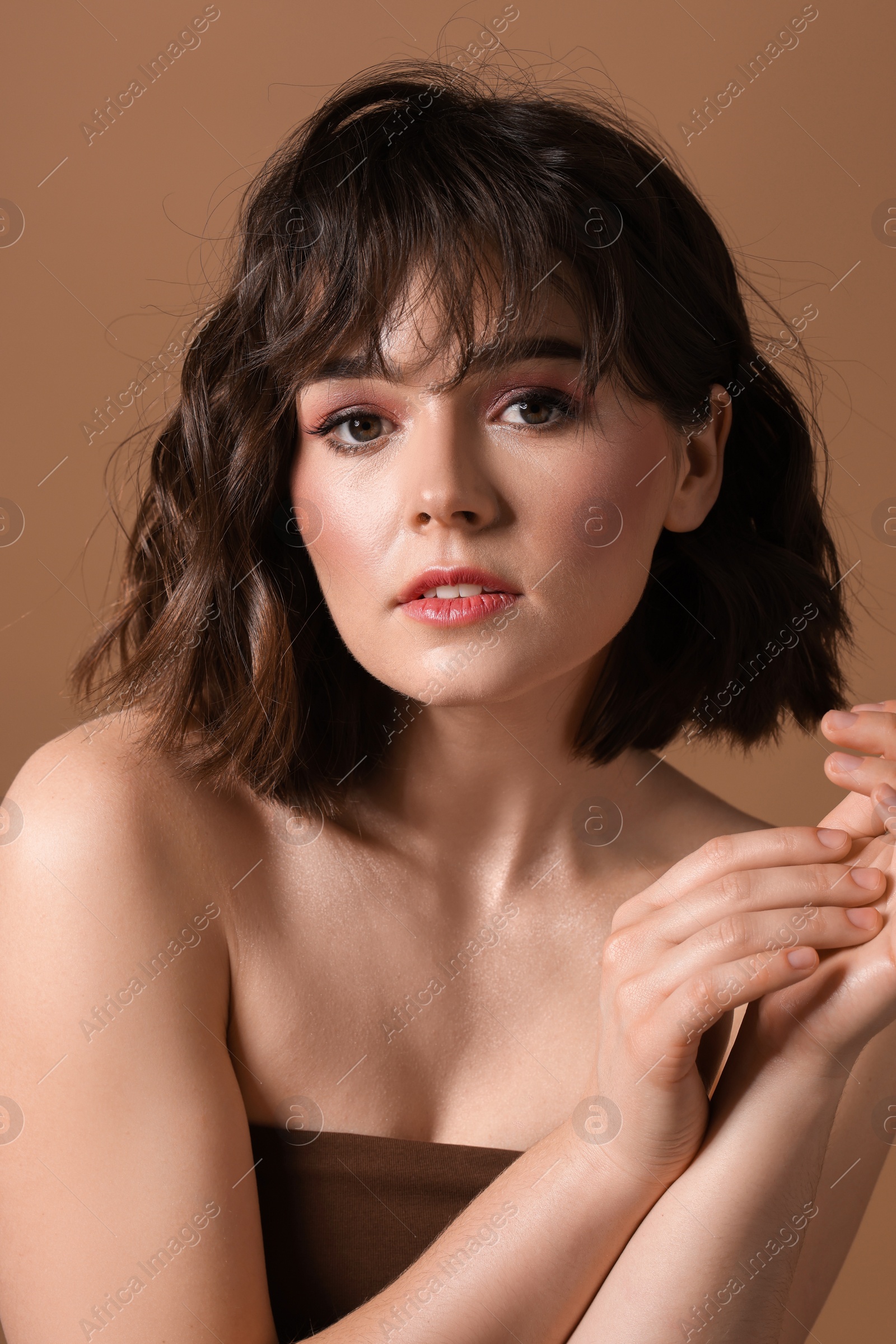 Photo of Portrait of beautiful young woman with wavy hairstyle on brown background