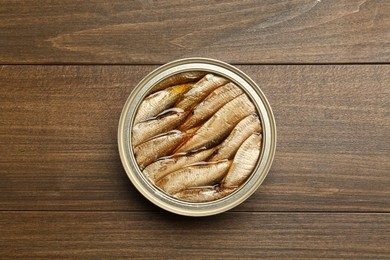 Photo of Sprats in tin can on wooden table, top view