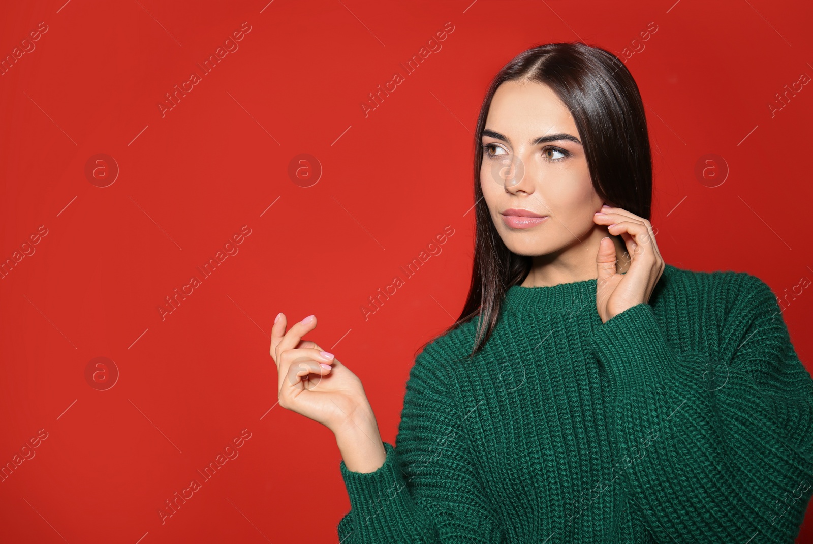 Image of Pretty woman wearing warm sweater on red background