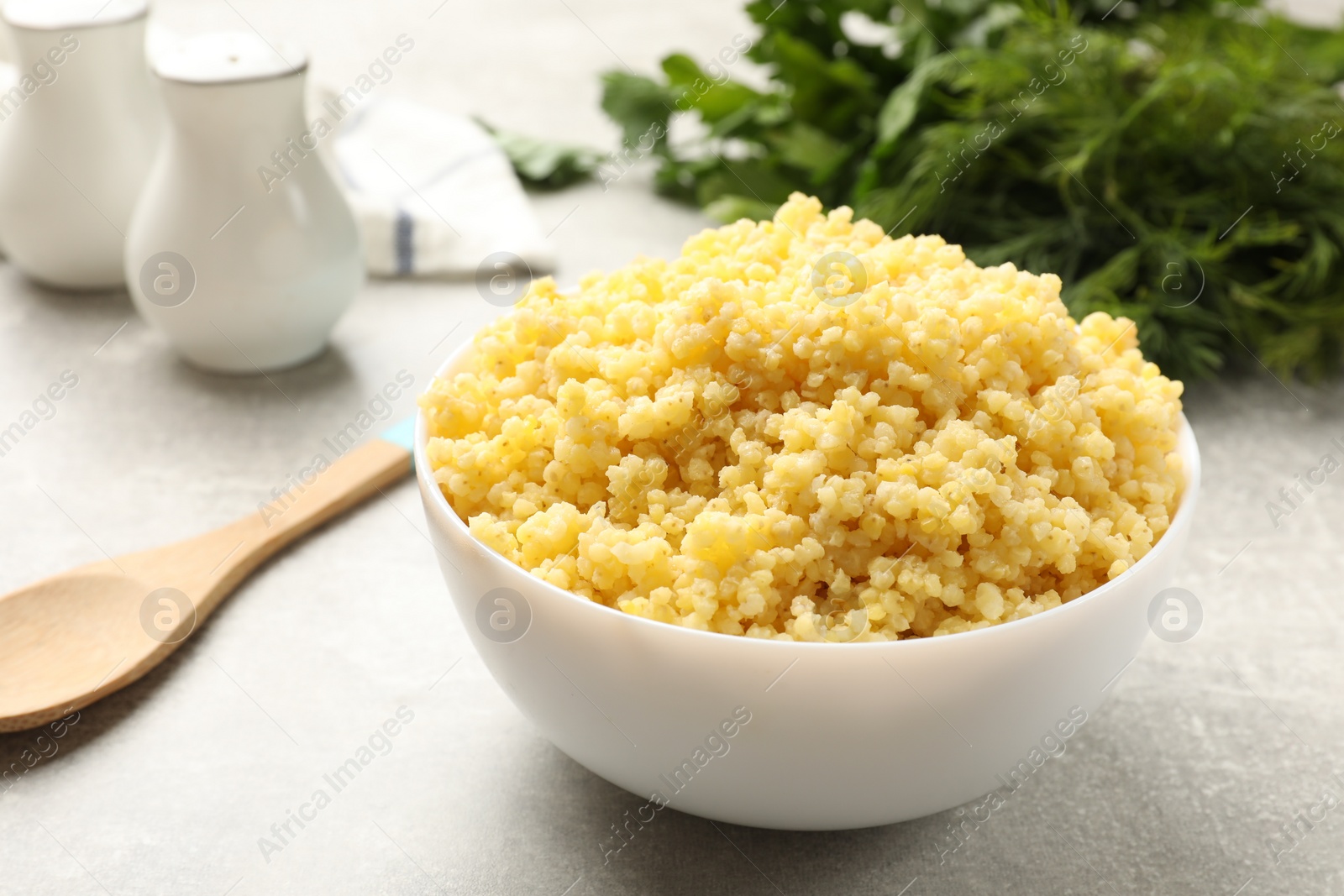 Photo of Tasty millet porridge on grey textured table, closeup