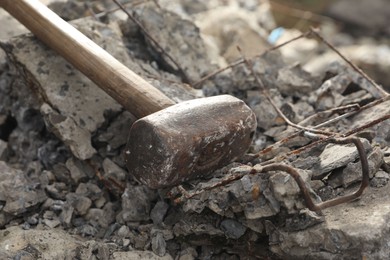 Photo of Sledgehammer on pile of broken stones outdoors, closeup