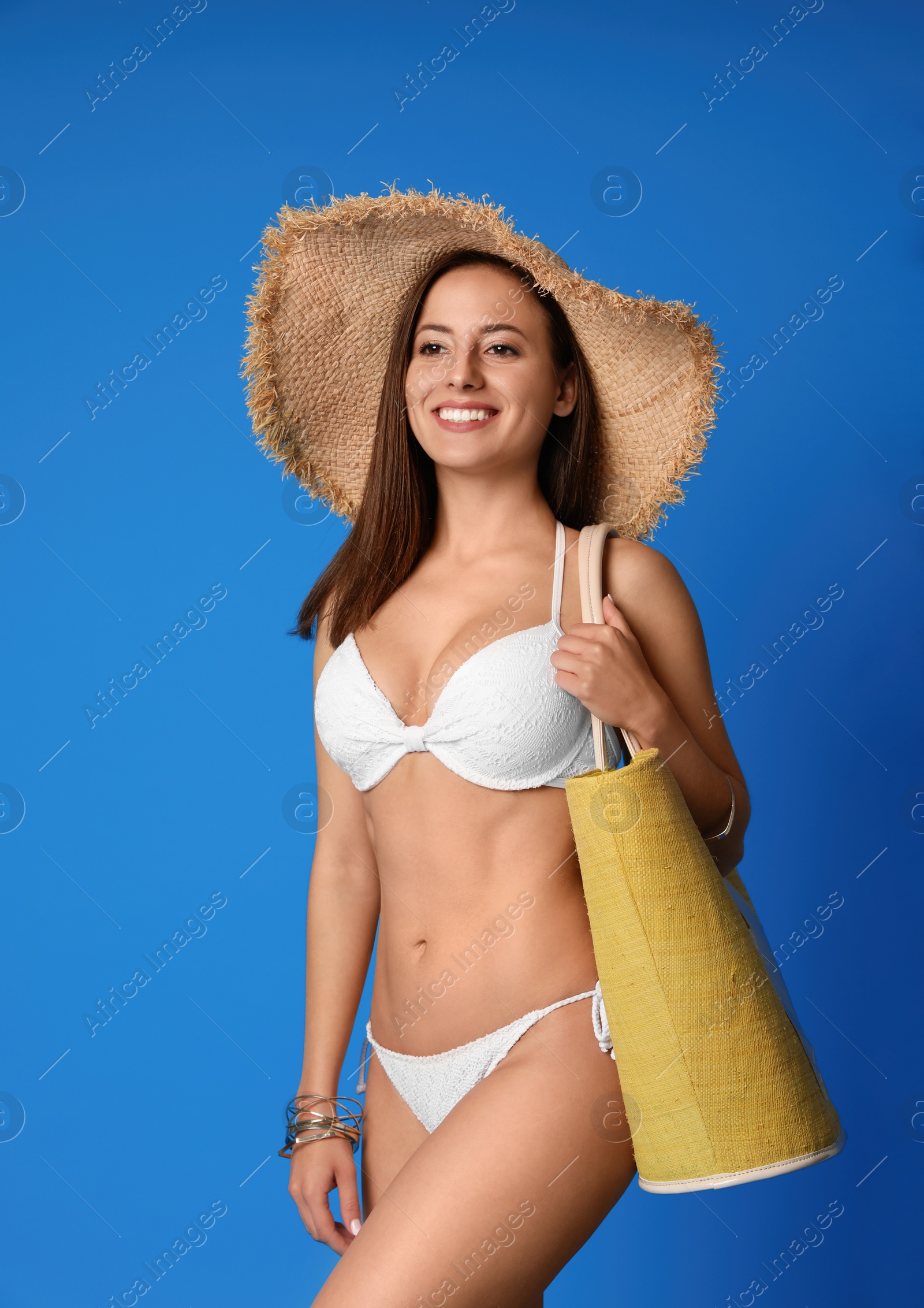 Photo of Pretty sexy woman with slim body in stylish  white bikini on blue background