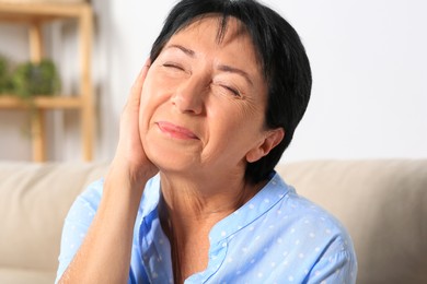 Senior woman suffering from ear pain at home