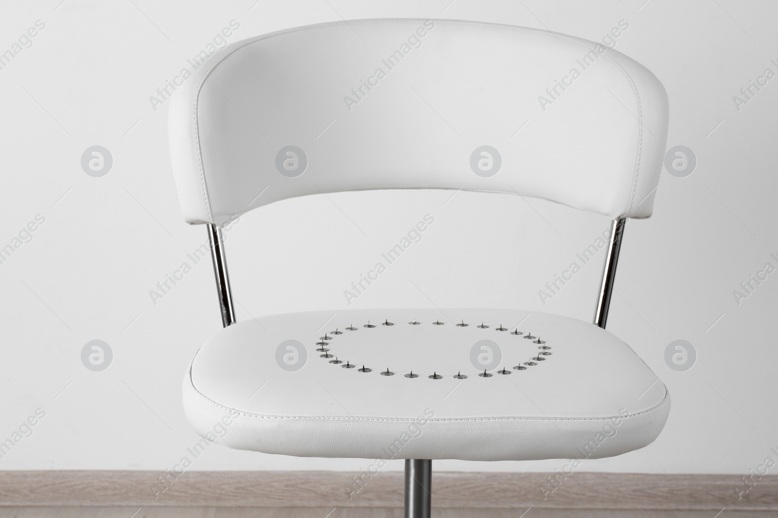 Photo of Chair with pins near white wall. Hemorrhoids concept