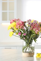 Vase with beautiful flowers on table in kitchen. Stylish element of interior design