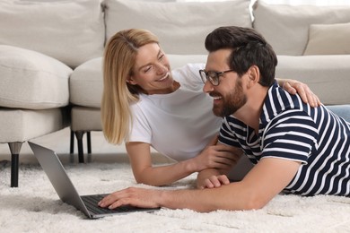 Photo of Happy couple with laptop on floor at home