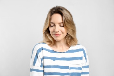 Portrait of happy young woman with beautiful blonde hair on light background