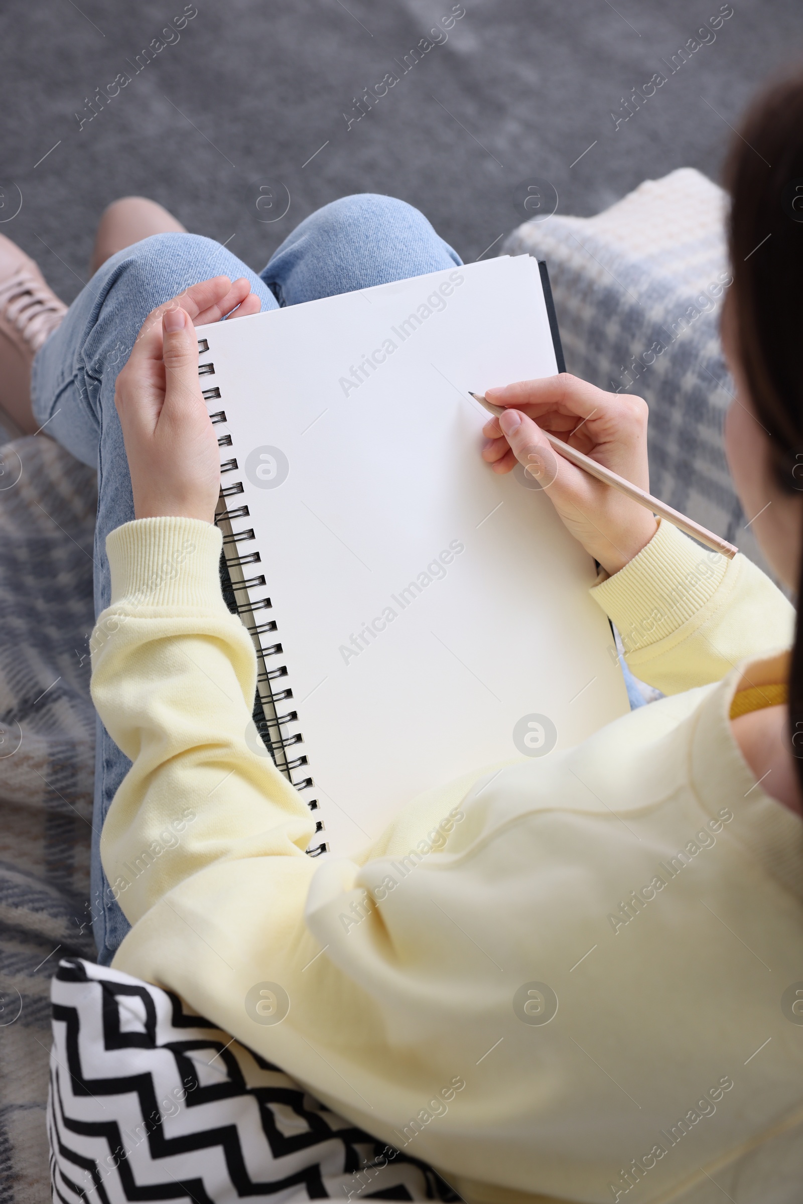 Photo of Young woman drawing in sketchbook indoors, closeup