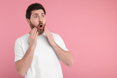 Photo of Portrait of surprised man on pink background, space for text