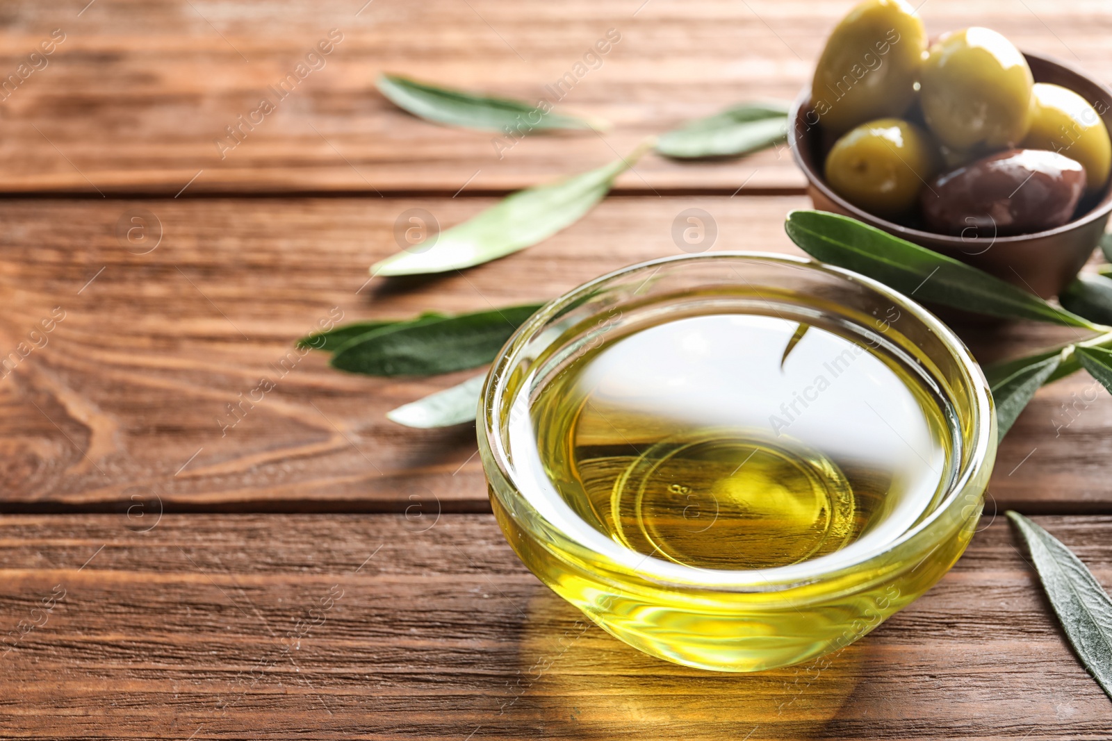 Photo of Bowls with olives and fresh oil on wooden table