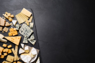 Photo of Cheese plate on black table, top view. Space for text