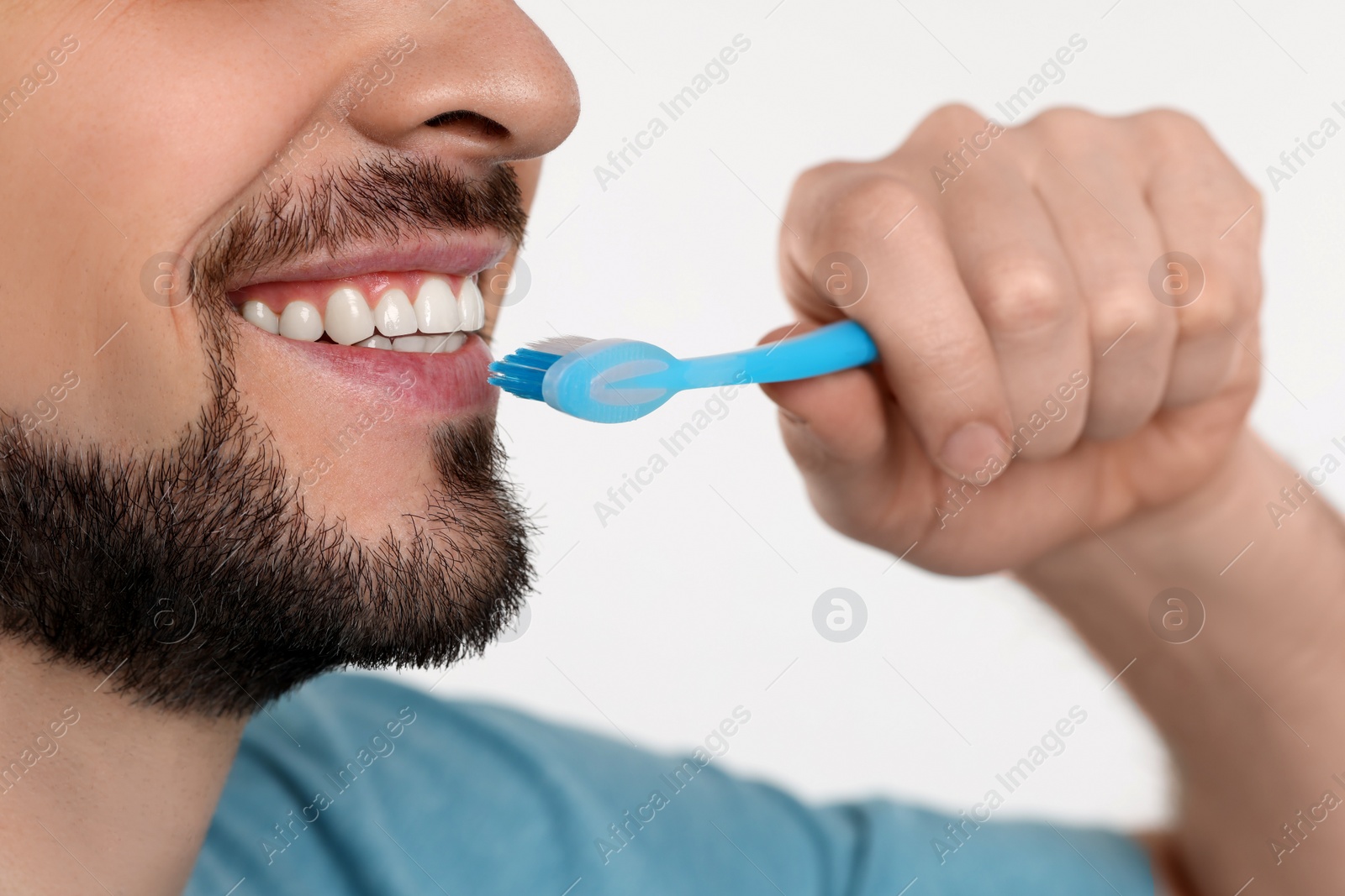 Photo of Man brushing his teeth with plastic toothbrush on white background, closeup