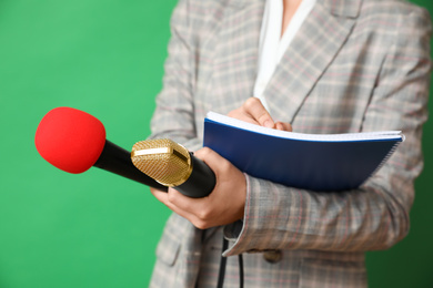 Journalist with microphones and notebook on green background, closeup