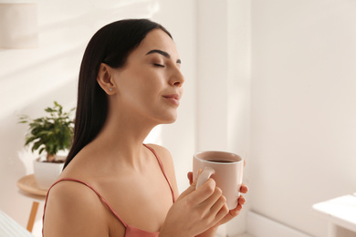 Woman with cup of tea in bedroom. Lazy morning