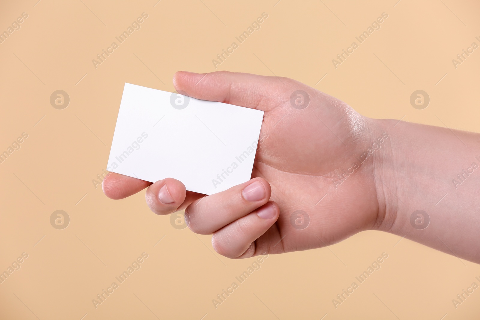 Photo of Man holding paper card on pale orange background, closeup. Mockup for design