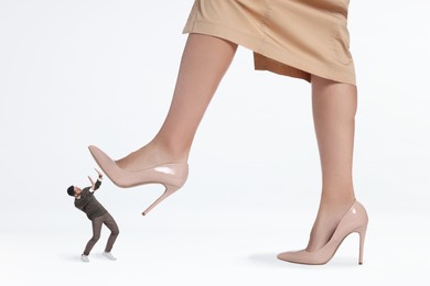 Image of Big woman stepping onto small man on white background