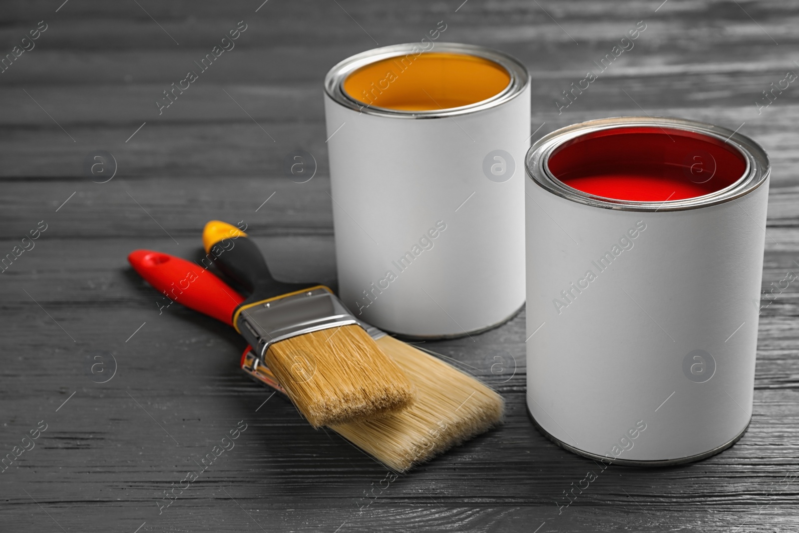 Photo of Open cans with paint and brushes on grey wooden table