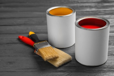 Photo of Open cans with paint and brushes on grey wooden table