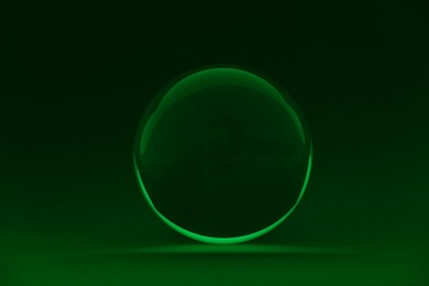 Photo of Transparent glass ball on dark green background