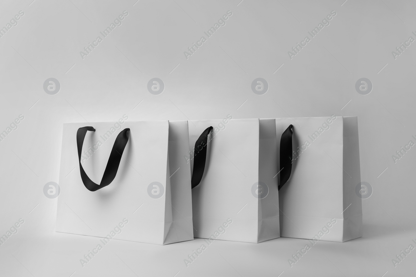 Photo of Paper shopping bags with ribbon handles on white background. Mockup for design