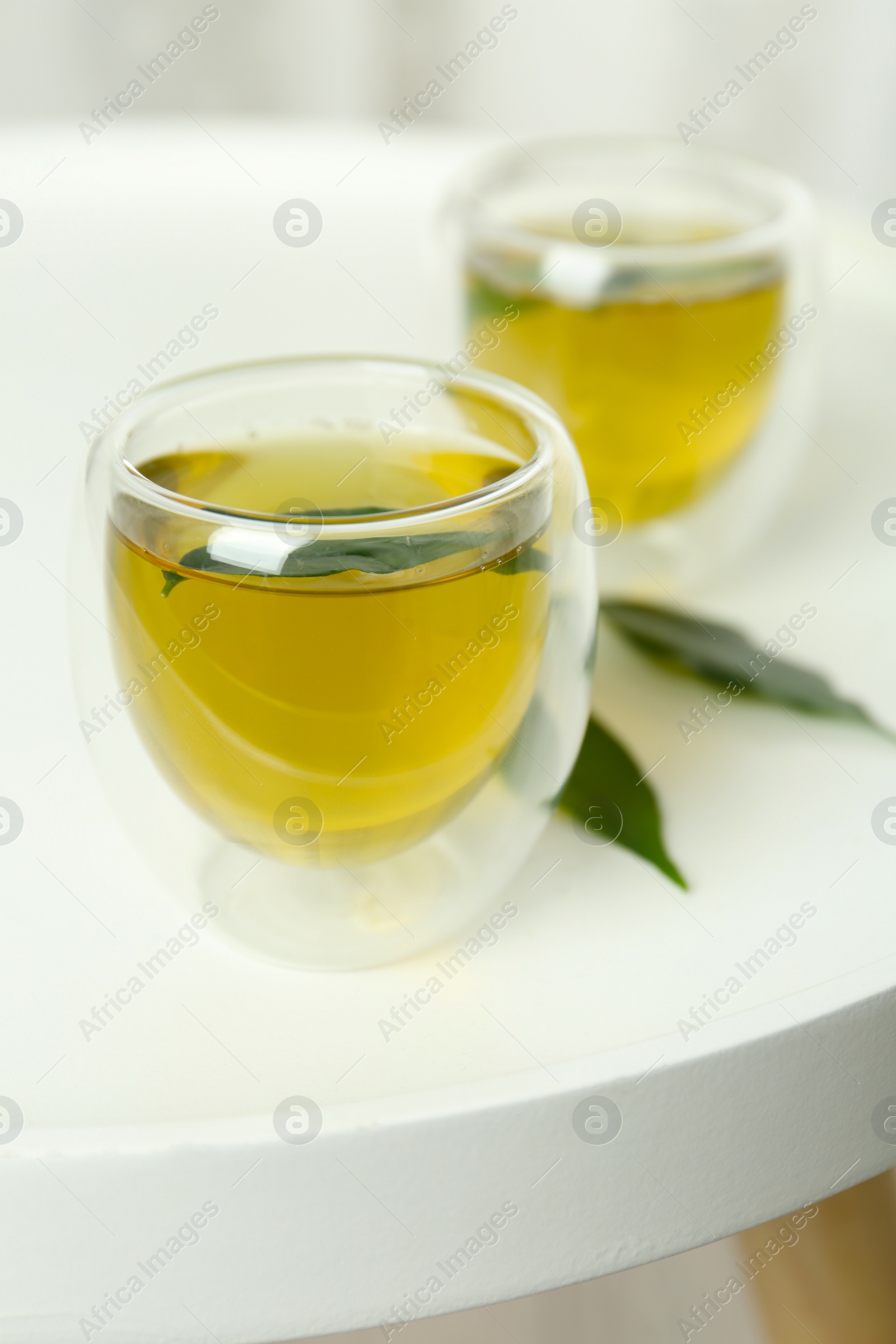 Photo of Aromatic green tea and leaves on white table