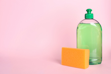 Detergent and sponge on pink background, space for text