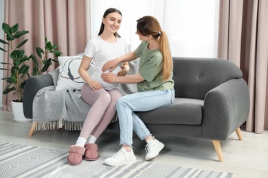 Doula taking care of pregnant woman on sofa at home. Preparation for child birth