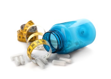 Photo of Jar of weight loss pills and measuring tape on white background