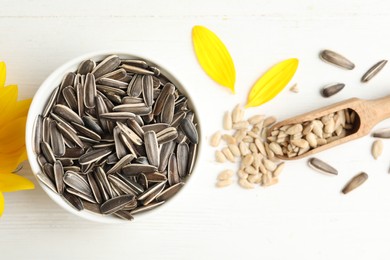 Photo of Organic sunflower seeds and scoop on white wooden table, flat lay