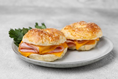 Photo of Delicious bagels with ham and cheese on light table, closeup