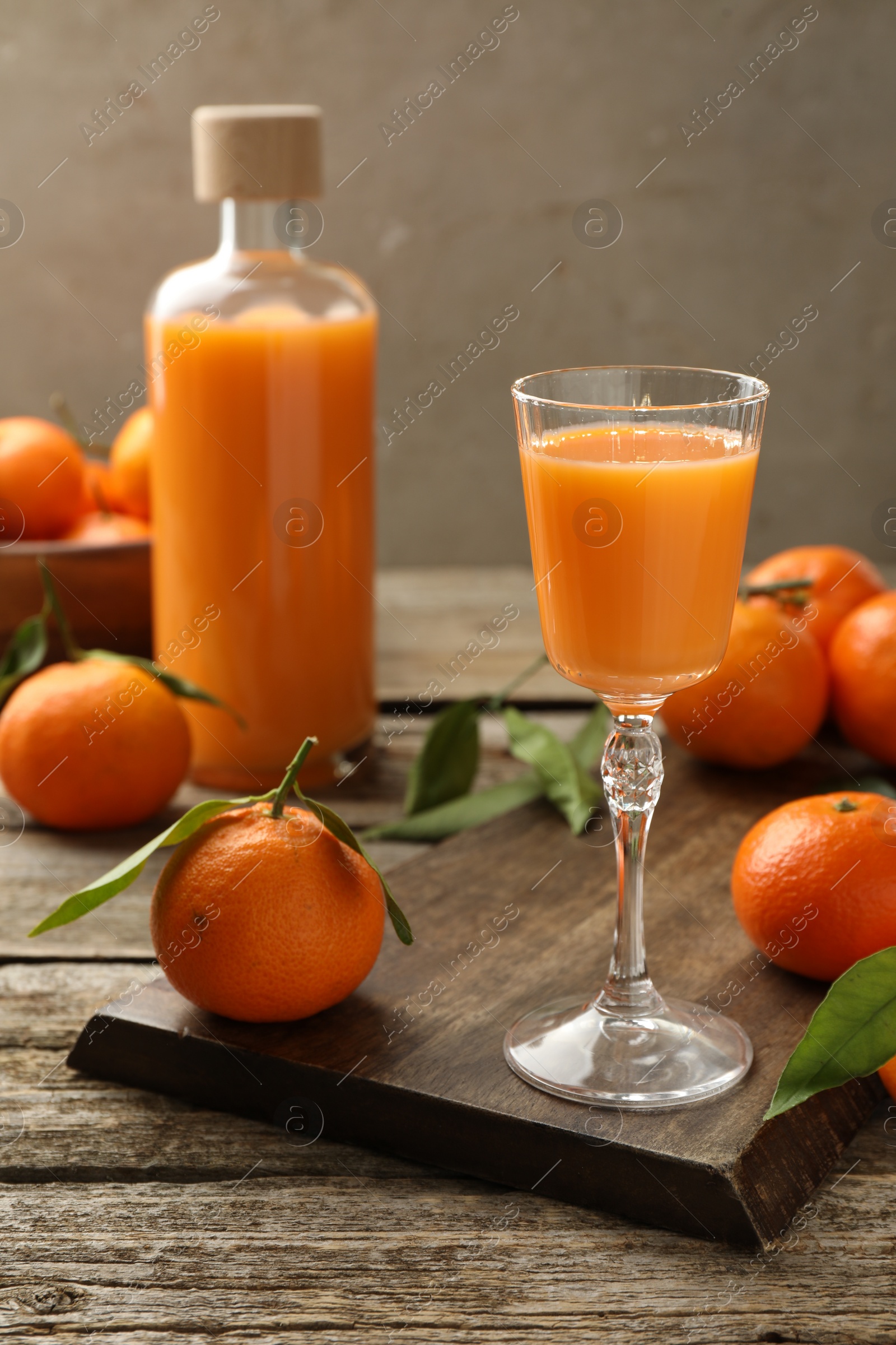 Photo of Delicious tangerine liqueur and fresh fruits on wooden table