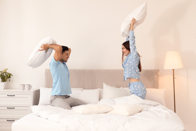 Happy couple having pillow fight in bedroom