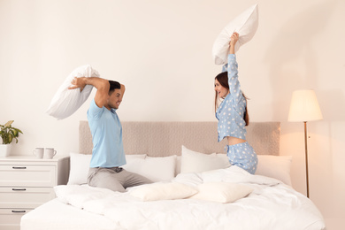 Photo of Happy couple having pillow fight in bedroom