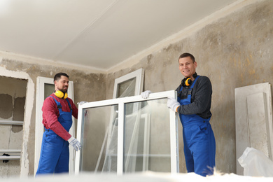 Photo of Workers in uniform with new plastic window indoors
