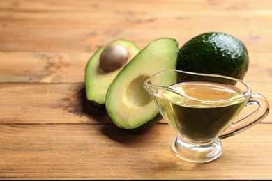 Photo of Composition with natural oil and avocados on wooden background. Space for text