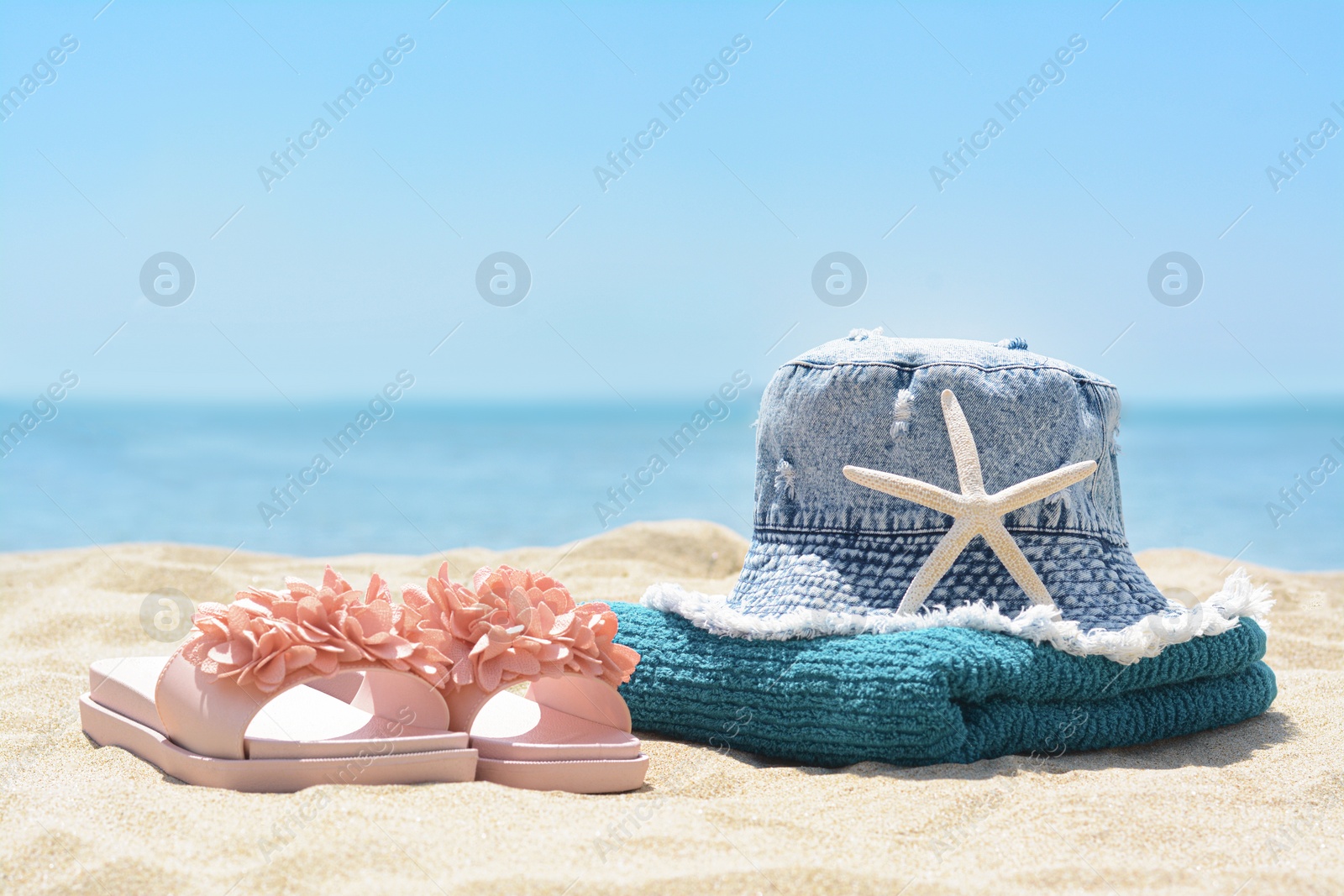 Photo of Stylish beach accessories on sand near sea