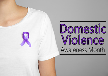 Woman with purple ribbon on grey background, closeup. Symbol of Domestic Violence Awareness 