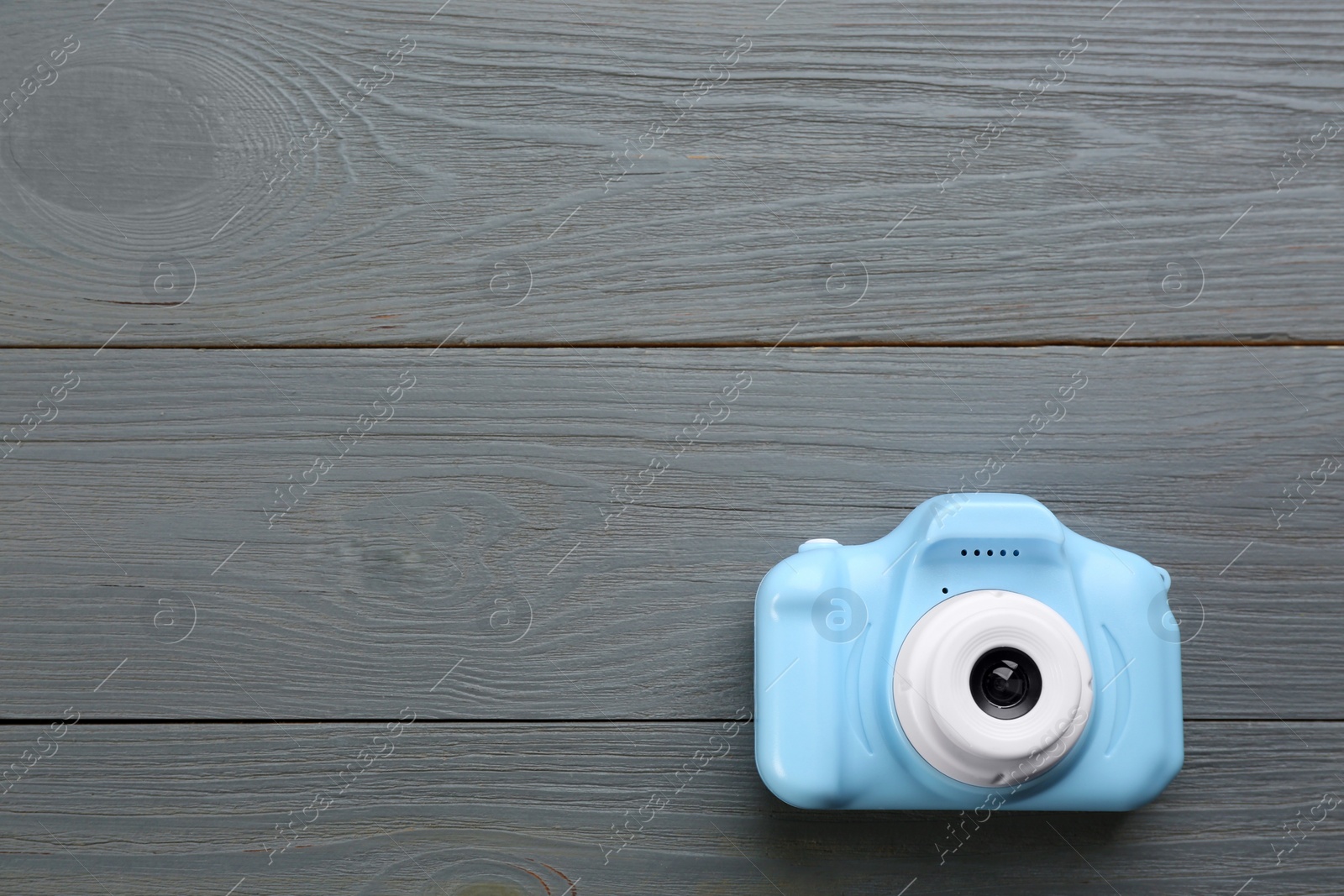 Photo of Light blue toy camera on grey wooden background, top view. Space for text