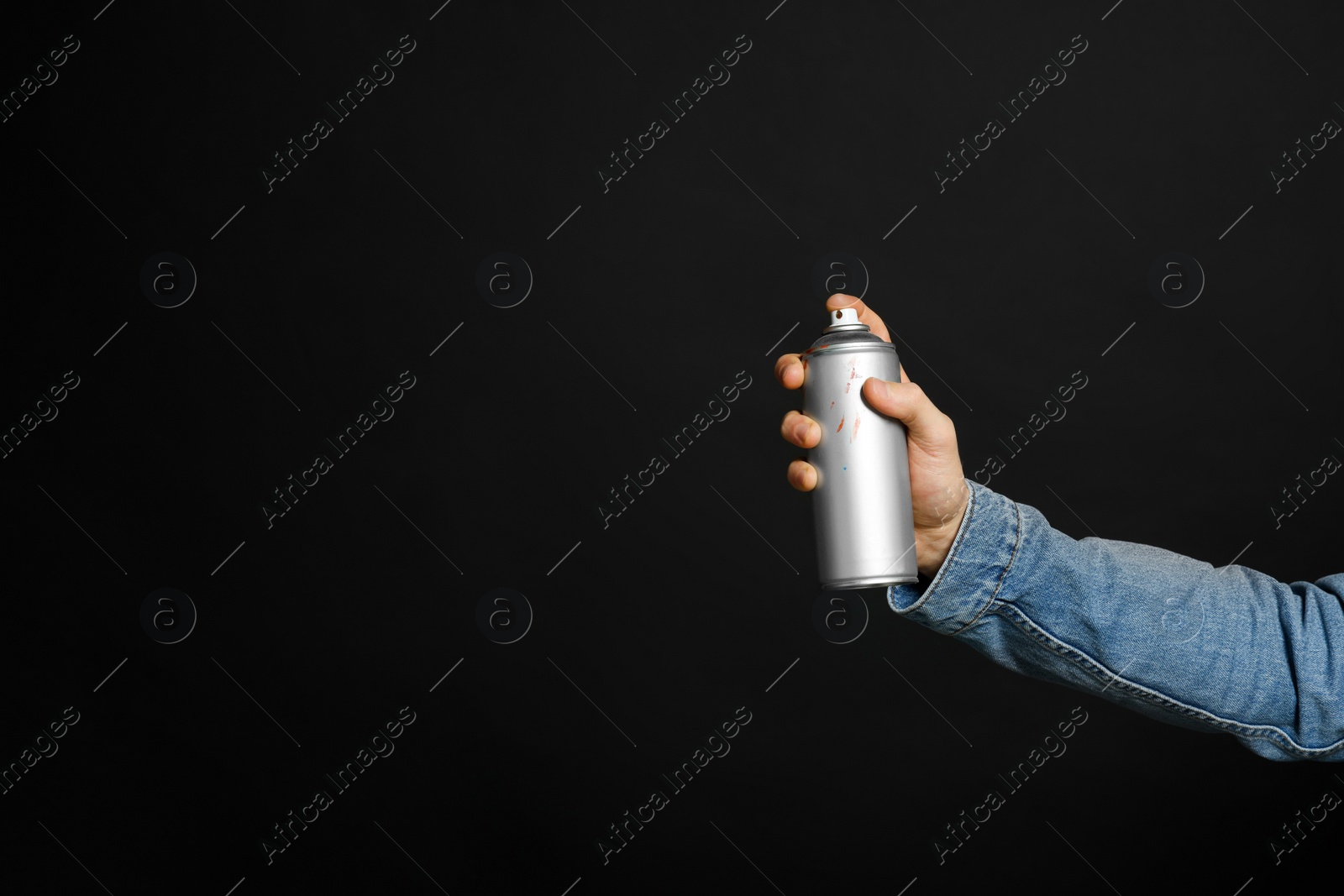 Photo of Man holding used can of spray paint on black background, closeup. Space for text