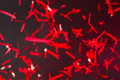 Photo of Shiny red confetti falling down on dark background