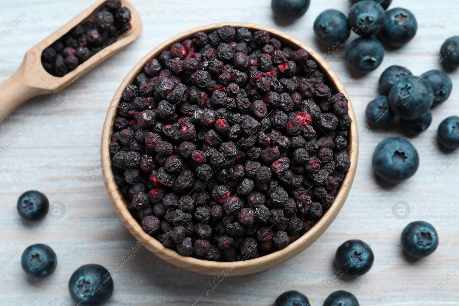 Photo of Freeze dried and fresh blueberries on white wooden table, flat lay