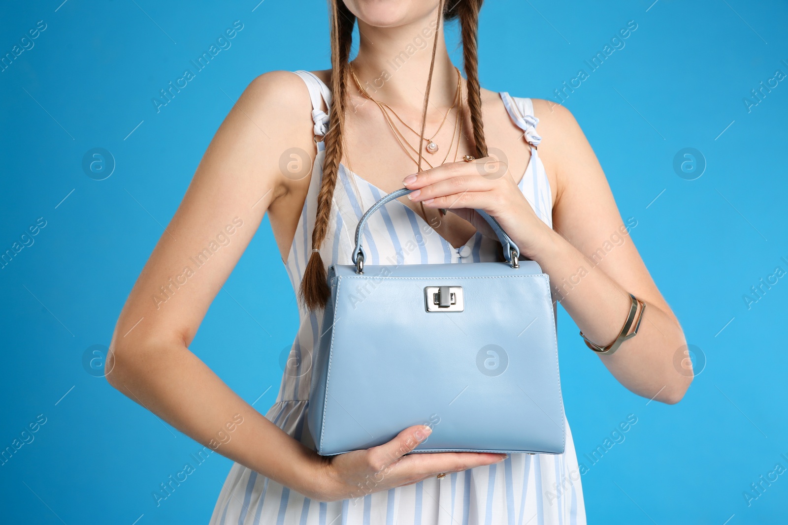 Photo of Young woman with stylish bag on light blue background, closeup