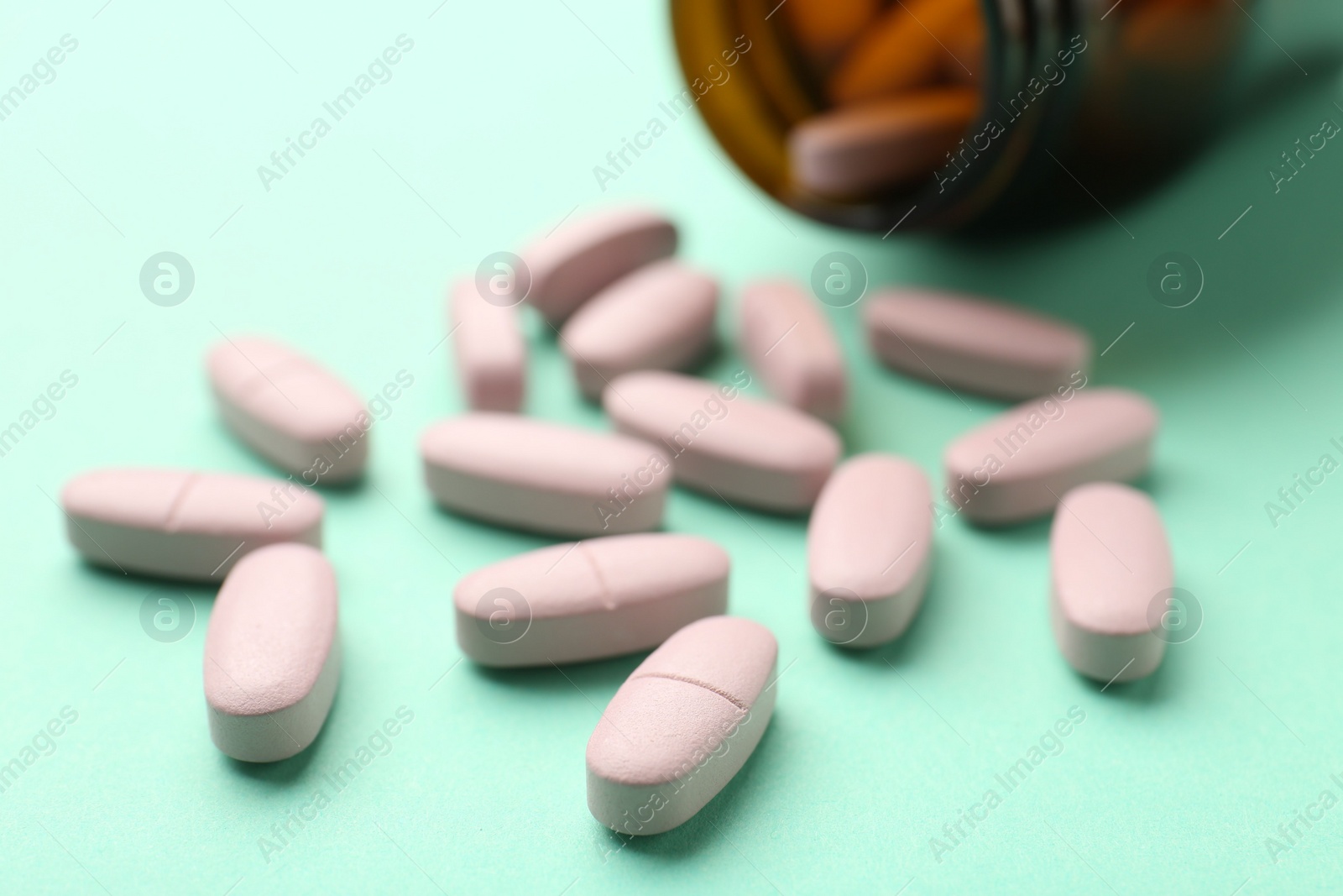 Photo of Vitamin pills on mint color background, closeup