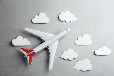 Toy airplane and clouds on grey stone background, flat lay