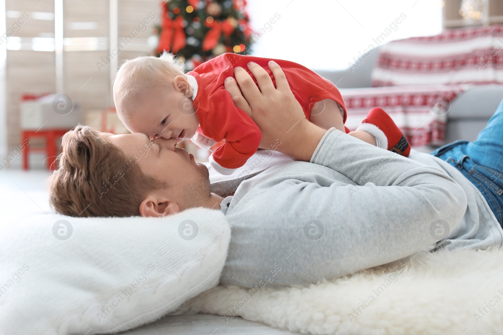 Photo of Young man with baby in Christmas suit at home