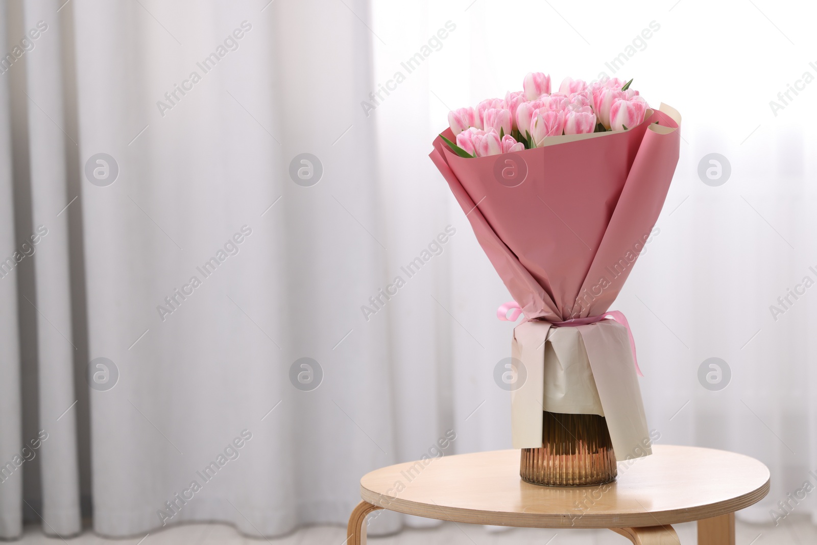 Photo of Beautiful bouquet of fresh pink tulips on table indoors. Space for text