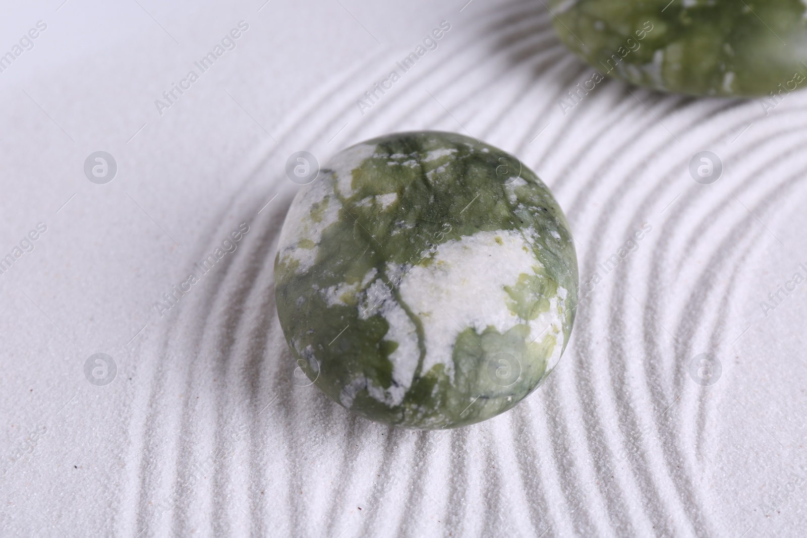 Photo of Zen concept. Stones and pattern on white sand, closeup